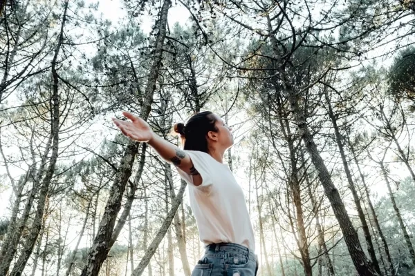 Woman breathing clean air in the forest with arms outstretched
