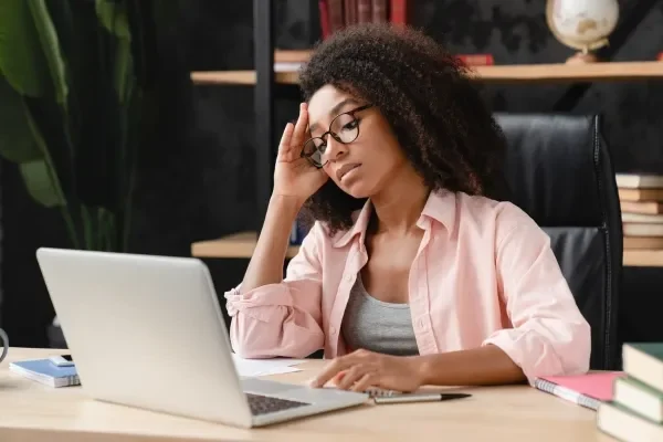 Woman suffering ferom a headache looking at her computer screen